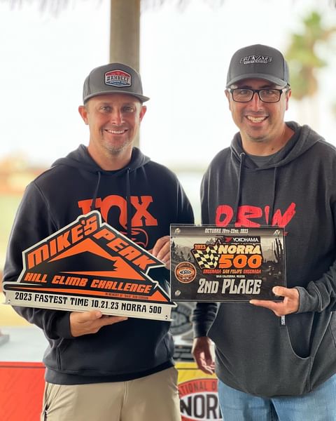 Justin Lofton holding awards for off road race norra 500 and mikes peak hill climb challenge